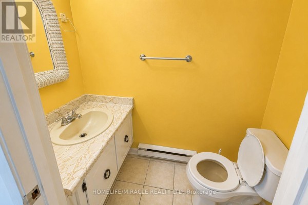 Powder room with bright yellow walls, white vanity, beige tile floor, and a toilet. - 74 - 2651 Aquitaine Avenue, Mississauga