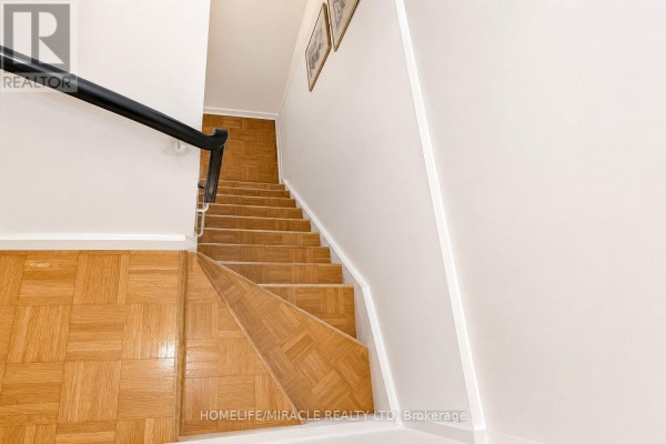 View from top of stairs looking down to wooden treads and parquet flooring. - 74 - 2651 Aquitaine Avenue, Mississauga