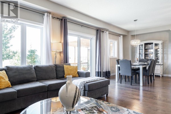 Living and dining area with a large grey sectional sofa, dining table with six chairs, and hardwood floors. - 74 Ahrens Drive, Stratford
