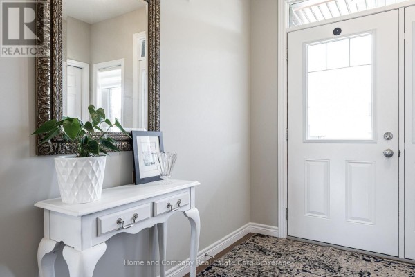 Entryway with a white console table, ornate mirror, potted plant, and a white double door with glass panes. - 74 Ahrens Drive, Stratford