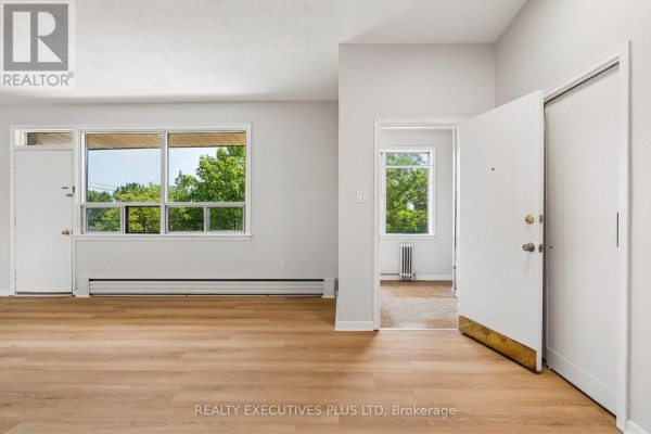 Interior view of a hallway with a large window, radiator, and a staircase. - 74 Calstock Drive, Toronto