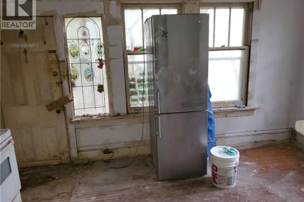 Kitchen area with a silver refrigerator, stained glass door, and empty cabinets. - 74 Carrick Avenue, Hamilton