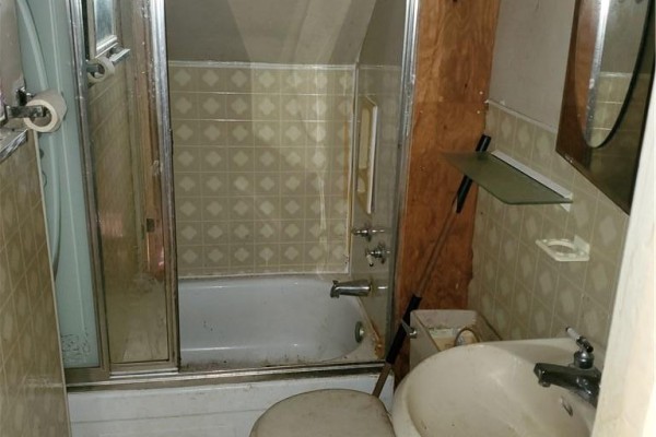 Bathroom with a bathtub, shower doors, sink, toilet, and tiled walls. - 74 Carrick Avenue, Hamilton