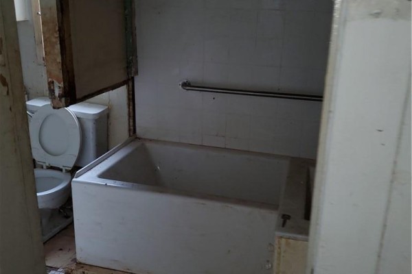 Bathroom featuring a white bathtub, toilet, and a metal grab bar. - 74 Carrick Avenue, Hamilton