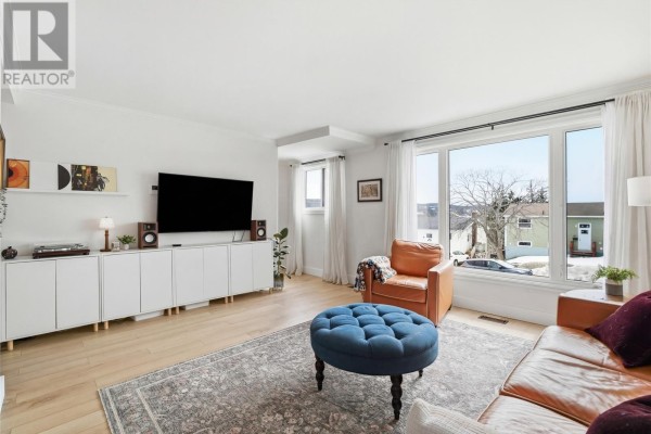 Living room features a large entertainment unit, black TV, and a bay window. - 74 Eastaff Street, St  Johns