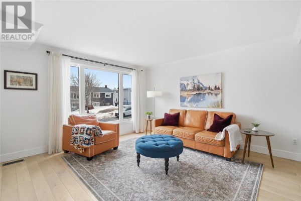 Living room with tan leather seating, a blue ottoman, and a large bay window view. - 74 Eastaff Street, St  Johns