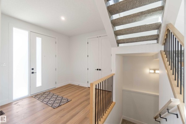 Foyer with glass double doors, wood-look flooring, and a staircase with light wood railing. - 74 Eldridge Pt, St  Albert