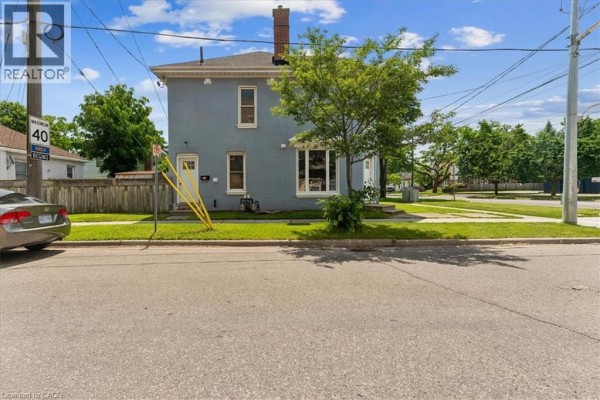 Front exterior view of the light blue brick house with a sidewalk and grass in front. - 74 Erie Avenue Unit# Upper, Brantford