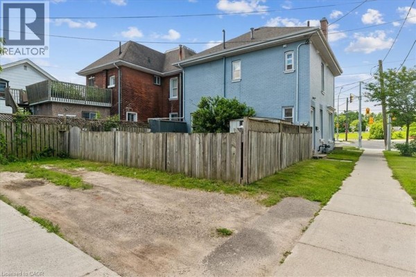Side angle exterior of the blue brick house showing the entrance porch and driveway. - 74 Erie Avenue Unit# Upper, Brantford