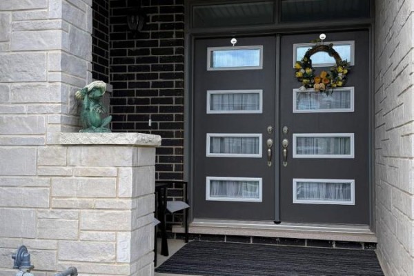 Close-up of the dark grey double front doors of a townhouse with glass panels. - 74 Forestwalk Street, Kitchener