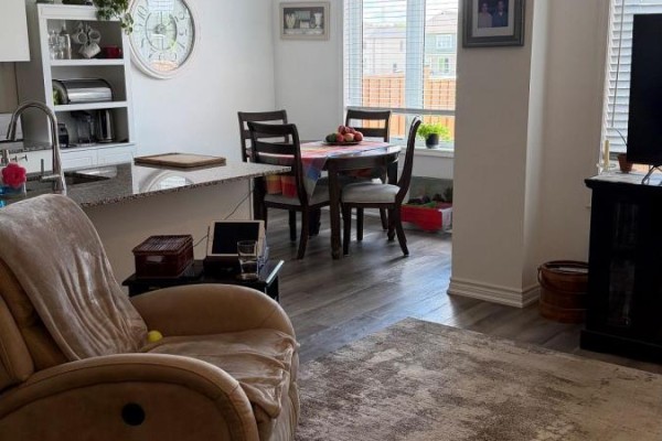 Dining area and kitchen with a breakfast bar, dining table, and white shelving. - 74 Forestwalk Street, Kitchener