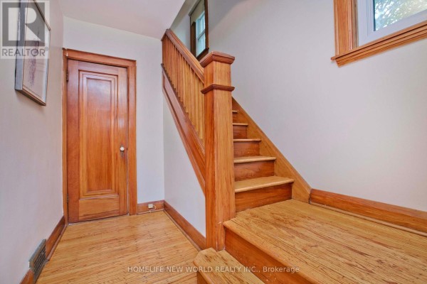 Wooden staircase with a light-colored railing and trim, leading to the second floor. - 74 Haddon Avenue N, Hamilton