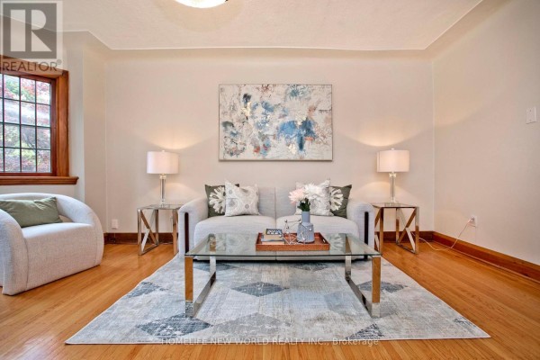 Living room with two sofas, a coffee table, and a large abstract painting on the wall. - 74 Haddon Avenue N, Hamilton