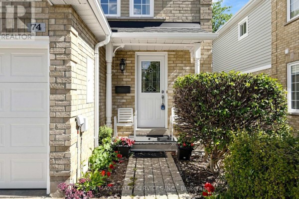 Entrance hallway with hardwood floors, a staircase with grey carpet and wooden banister, and white doors. - 74 Heathcliffe Square, Brampton