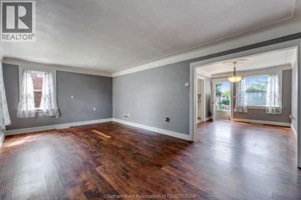 Living room with grey walls, dark wood floors, and white lace curtains on windows. - 74 Marlborough Street East, Leamington
