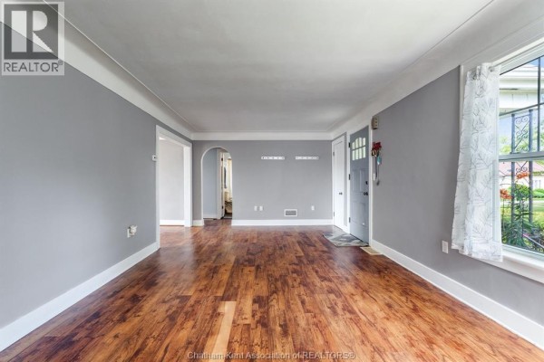 View of the living room showing the entrance door and a window with curtains. - 74 Marlborough Street East, Leamington