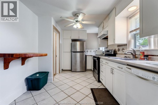 White kitchen with stainless steel appliances, white cabinets, and tiled floor. - 74 Marlborough Street East, Leamington