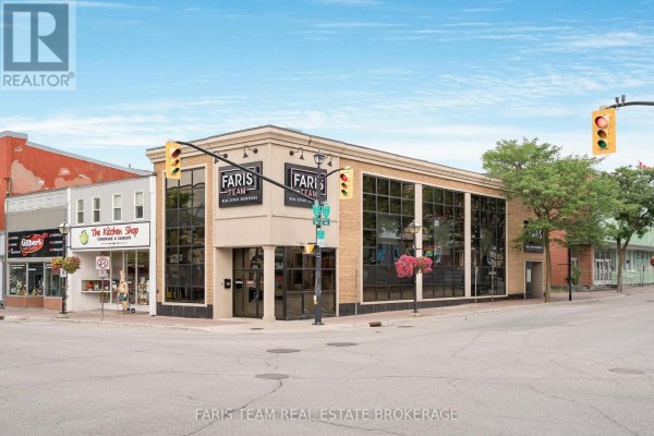 Exterior view of the commercial building from the street, showing the brick facade and adjacent storefronts. - 74 Mississaga Street E, Orillia