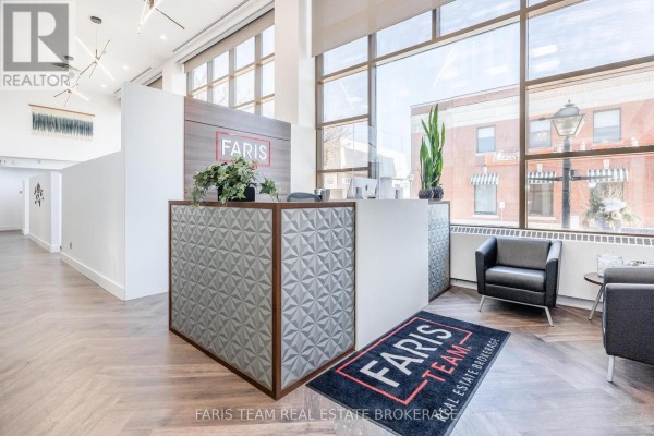 Office reception desk with computers, coffee station, and large windows overlooking the street. - 74 Mississaga Street E, Orillia
