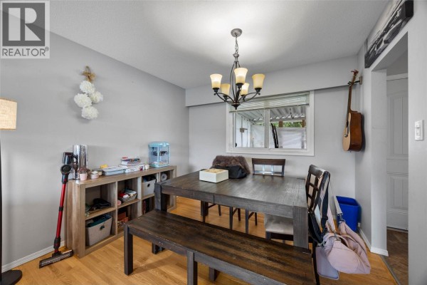 Dining area with wooden table, bench, chandelier, and view of backyard. - 740 Sherwood Drive, Kamloops