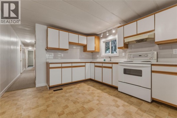 Storage room with wood shelving units against a beige wall and a white chest freezer. - 7400 Pleasant Valley Road Unit# 34, Vernon