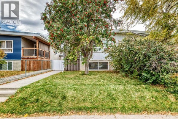 Exterior view of a duplex with a front lawn and mature trees. - 7409 37 Avenue Nw, Calgary
