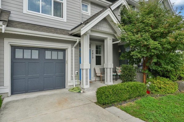 Close-up of the front entrance of a townhouse with a grey garage door and decorative columns. - 7419 Preston Boulevard, Mission
