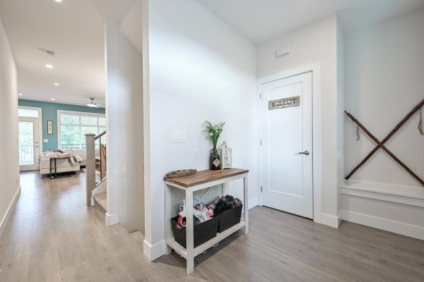 Interior hallway with light wood floors, a white door, and a console table with baskets. - 7419 Preston Boulevard, Mission