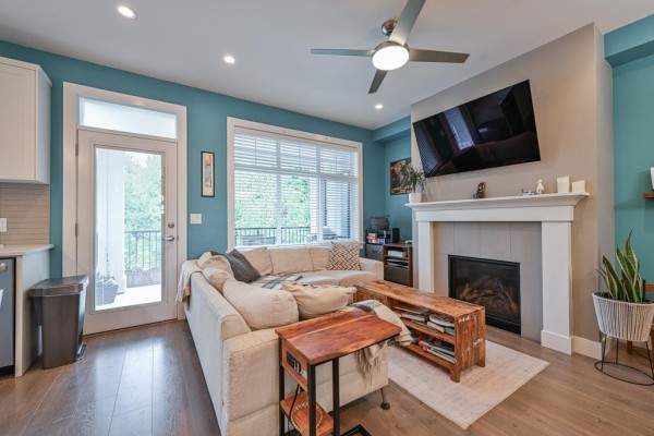 Living room with a large sectional sofa, fireplace, television, and blue walls. - 7419 Preston Boulevard, Mission