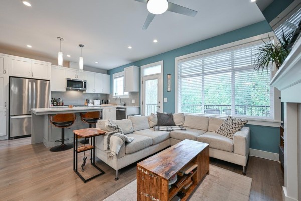 Open concept living room and kitchen with a sectional sofa, fireplace, and white cabinetry. - 7419 Preston Boulevard, Mission