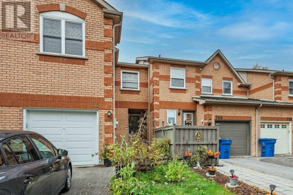 Street view of a brick townhouse complex with garages and driveways. - 742 Shanahan Boulevard, Newmarket