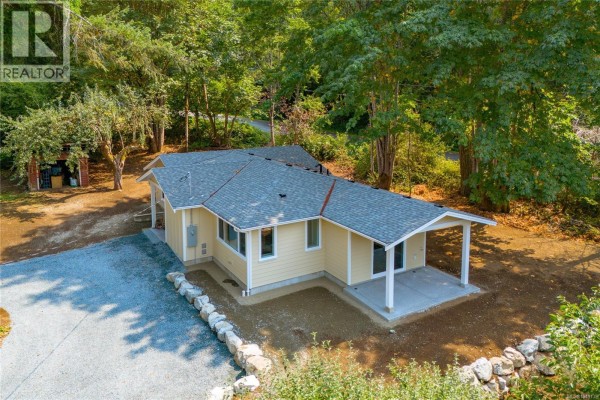 Lush green trees and foliage line a dirt path leading towards a distant mountain. - 7421 Westholme Rd, Westholme