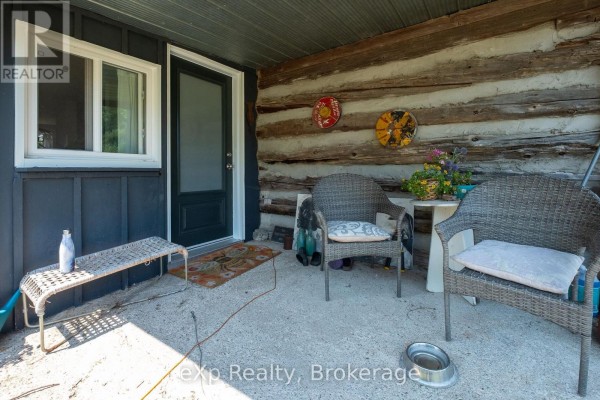 Covered porch with two wicker chairs, a small table, and a dog bowl. - 742649 Sideroad 4b, Chatsworth