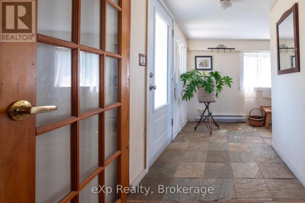 Interior hallway with wood trim glass doors, tile flooring, and a white door. - 742649 Sideroad 4b, Chatsworth