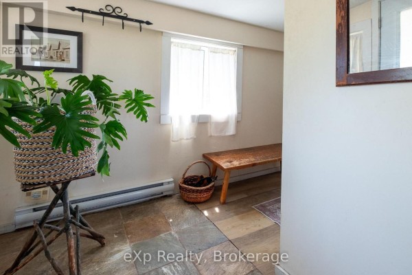 Hallway with a large plant, a wooden bench, a basket, and a baseboard heater. - 742649 Sideroad 4b, Chatsworth