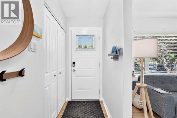 Interior foyer with white walls, a white door, double closet, and a large round mirror. - 7427 Fountain Road Se, Calgary