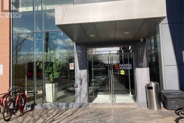 Entrance to 5 Hanna Avenue with glass doors, potted plant, and bicycles. - 743 - 5 Hanna Avenue, Toronto