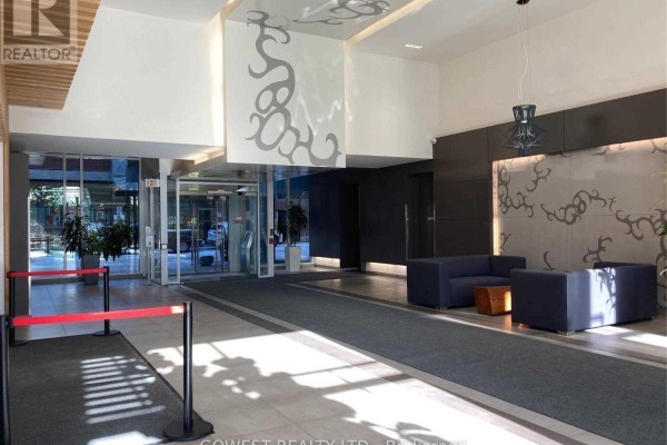 Lobby with dark blue sofas, modern art, and a grey carpeted walkway. - 743 - 5 Hanna Avenue, Toronto