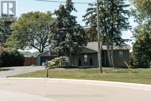 Exterior view of the house and detached garage from the side, showing the driveway and landscaping on a sunny day. - 7433 5 Side Road, Halton Hills