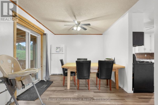 Dining area with a wooden table, black chairs, white refrigerator, and a sliding glass door to the outdoors. - 7437 A Hwy 620, Limerick
