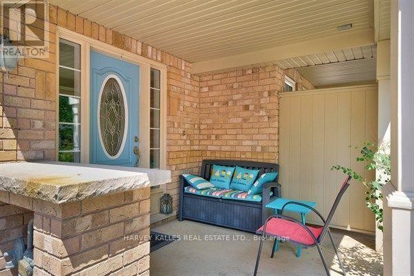 Covered front porch with blue door, brick columns, and outdoor seating. - 745 Challinor Terrace, Milton