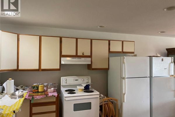A kitchen with white appliances, light beige cabinets, and a white stove on a grey wall. - 7475 Anglemont Way, Anglemont