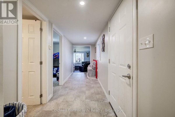 Interior hallway with light gray walls, white doors, and tiled flooring, leading to rooms. - 748 Arthur Street, West Grey