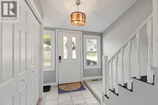 Entrance hallway with a white door, windows, tile flooring, and a staircase. - 748 Scratch Lane, Kingsville