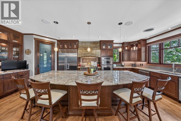 Open-concept living area with hardwood floors, a curved wooden staircase, and large windows. - 7495 Sun Valley Place, Radium Hot Springs