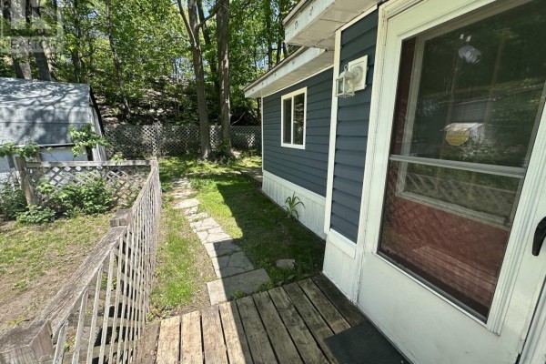 Interior view of a small sunroom with a glass sliding door and exterior view. - 75 - 1007 Racoon Road, Gravenhurst