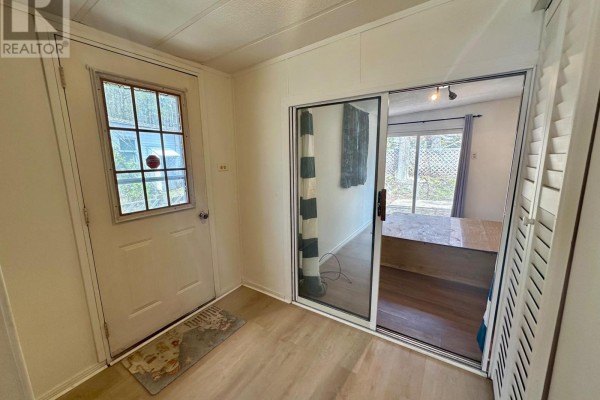 Living room of a mobile home with wood paneling, electric fireplace, and parquet flooring. - 75 - 1007 Racoon Road, Gravenhurst