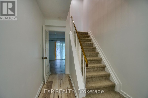 Bedroom with light wood laminate flooring, white walls, and a view into hallway. - 75 - 90 Lightfoot Place, Ottawa