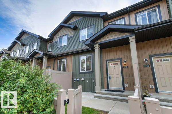 Exterior of townhouses featuring beige and green siding with covered entryways. - #75 3305 Orchards Link Li Sw, Edmonton