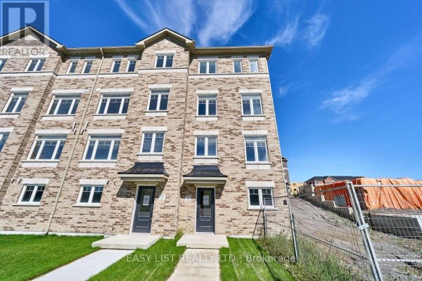 Exterior view of brick townhouse complex with green lawn and cloudy sky. - 75 Addyman Crescent, Clarington